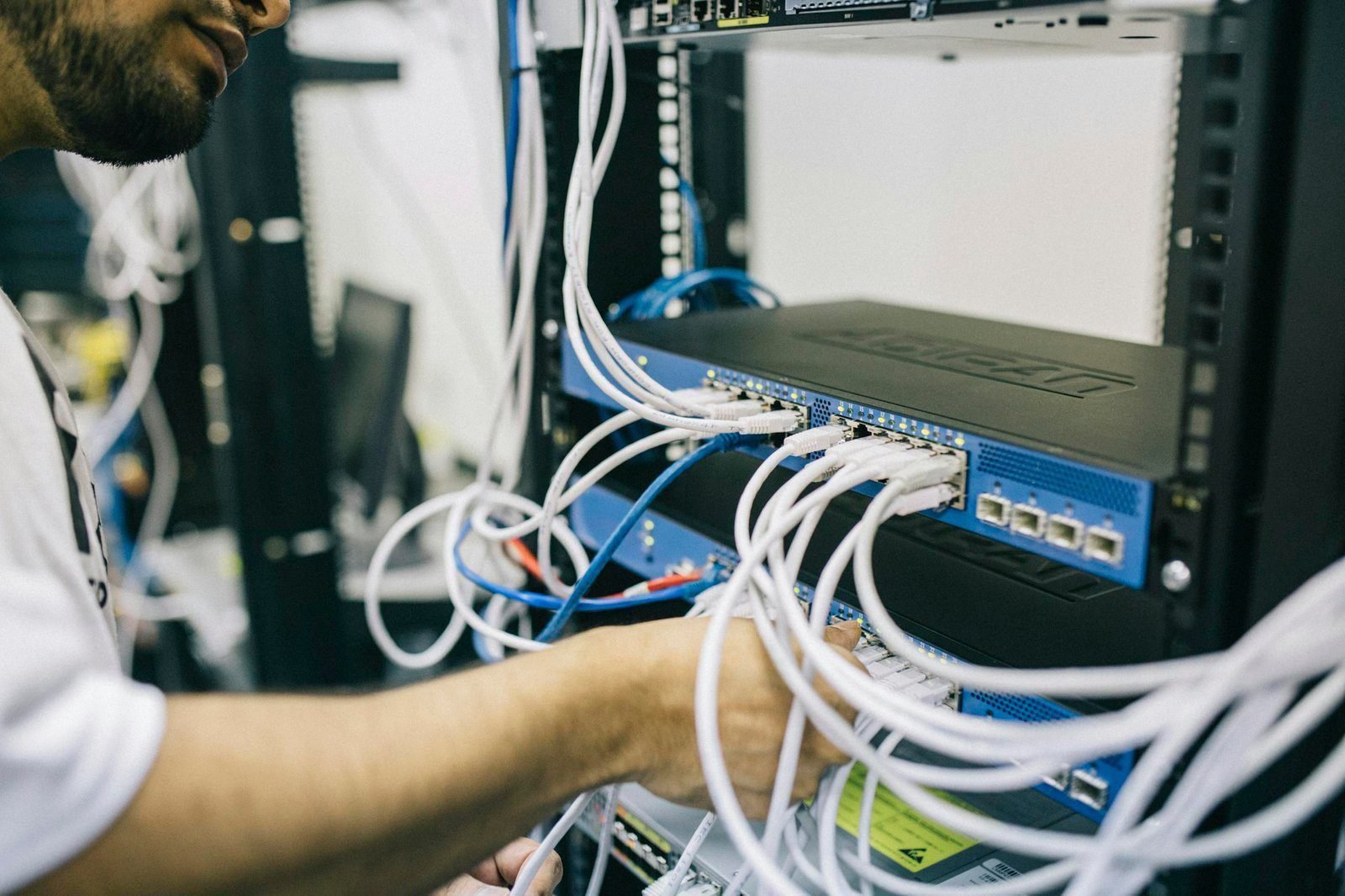 Case Study – Ethernet rehomes for decommissioning of New York Switch 1 An IT professional configuring network cables in a server rack, focusing on Ethernet connections.