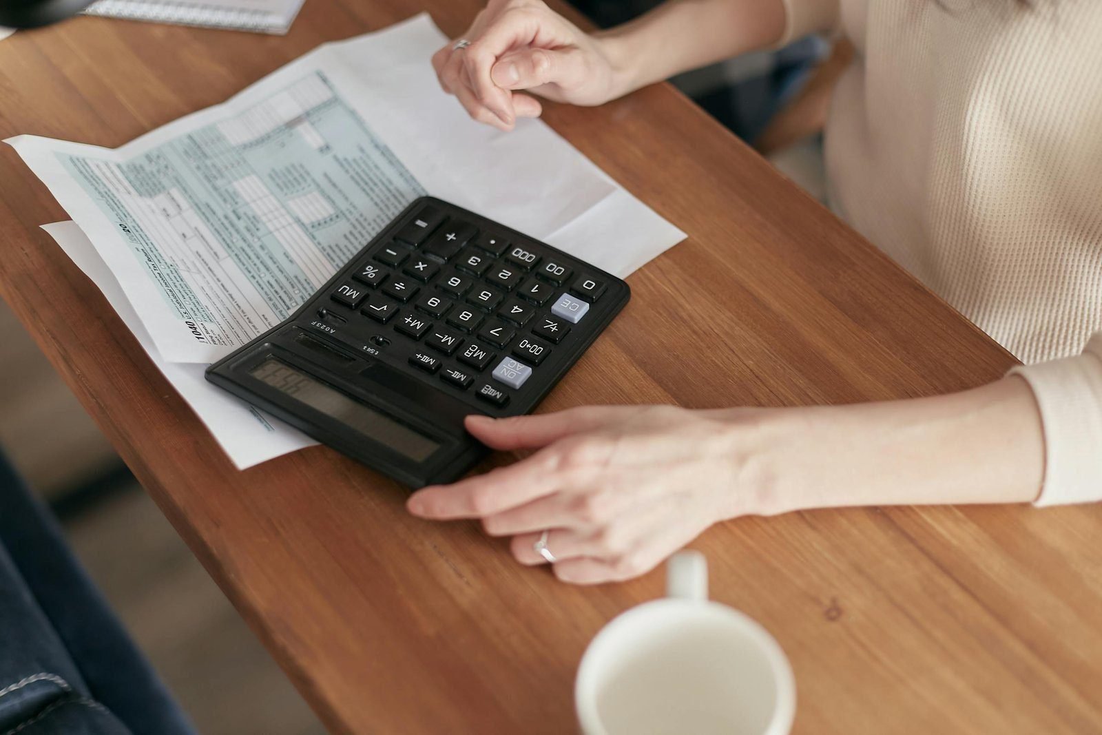 Recouping wireless and wireline circuit costs 1 Focused individual using calculator to manage personal finances at wooden desk.